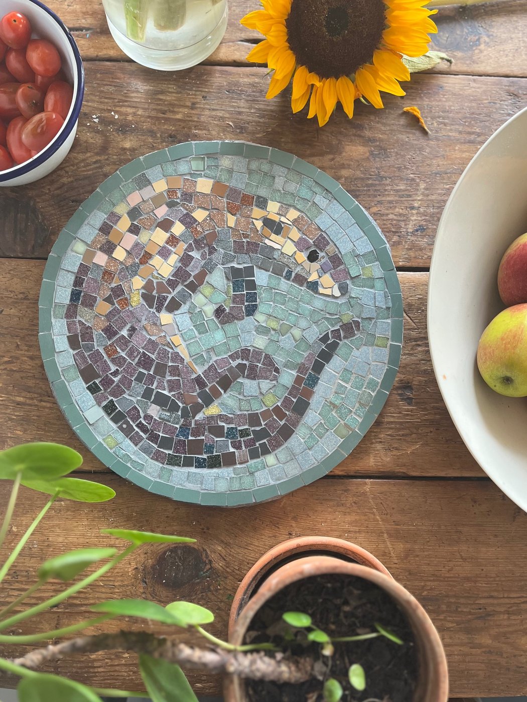 Circular mosaic of an otter in classical Roman style using small tiles in earth tones